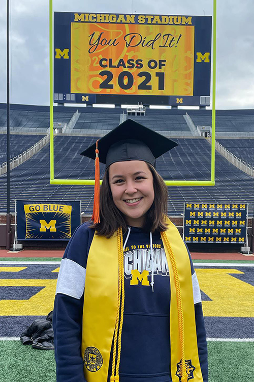 Michelle in grad cap and sash on the field of the Big House